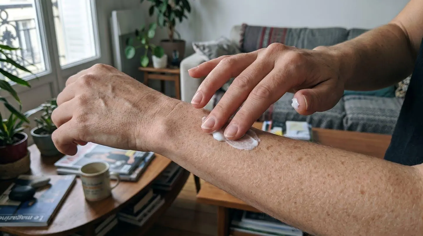 Main de femme appliquant délicatement une crème cosmétique sur l'avant-bras, geste doux, texture de peau naturelle visible