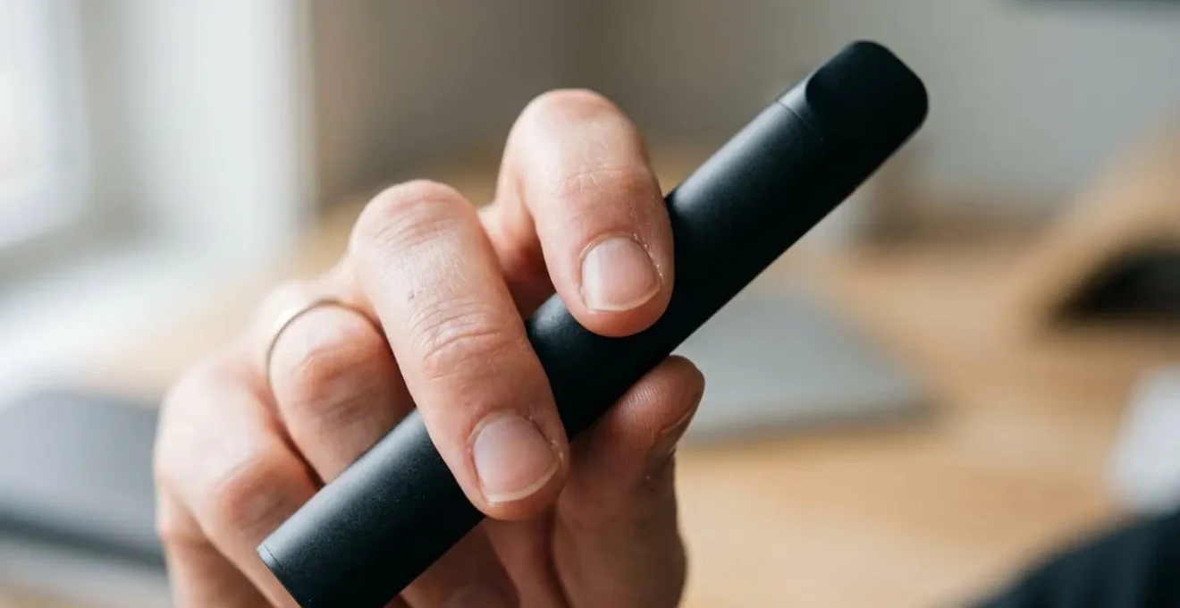Gros plan sur une main tenant une vape CBD avec technique d'inhalation précise